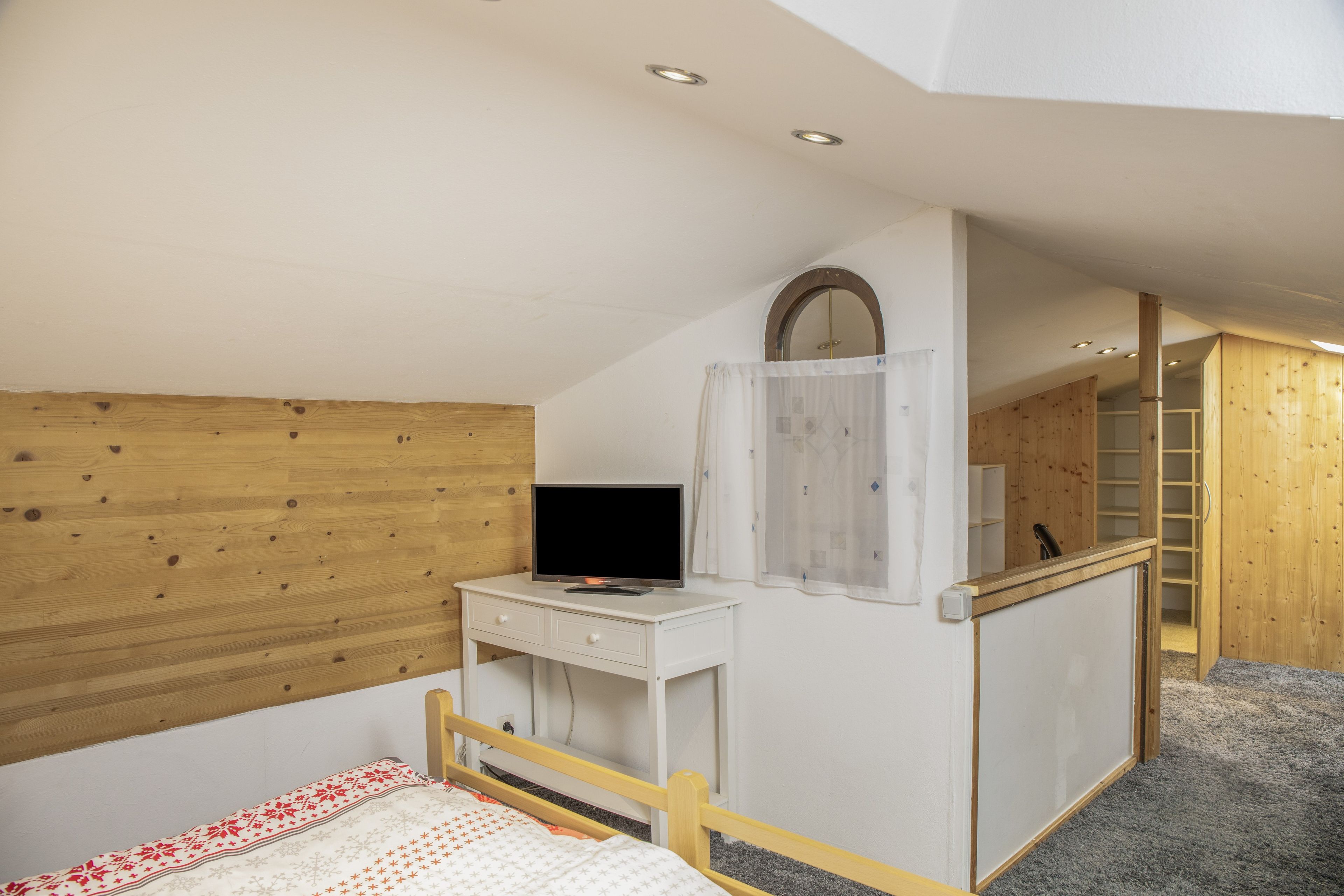 Ein Schlafzimmer mit einem hölzernen Kopfteil, einem Nachttisch mit Fernseher, einem Kleiderschrank und einem Spiegel.