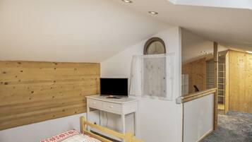 Ein Schlafzimmer mit einem hölzernen Kopfteil, einem Nachttisch mit Fernseher, einem Kleiderschrank und einem Spiegel.