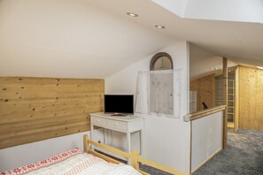 Een slaapkamer met een houten hoofdbord, een nachtkastje met een televisie, een garderobe en een spiegel.