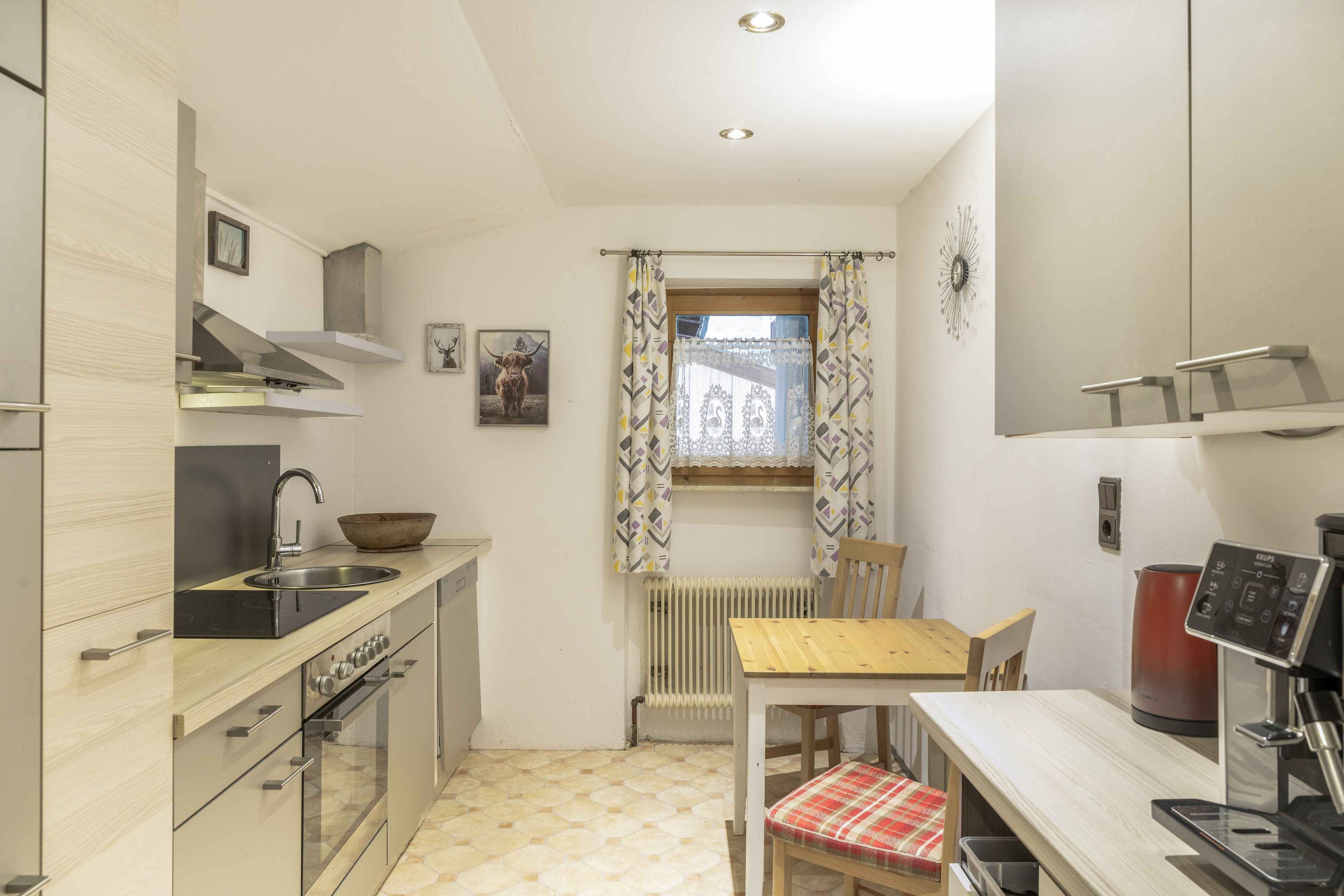 A compact kitchen with a sink, stove, and a dining area with a table and chairs.