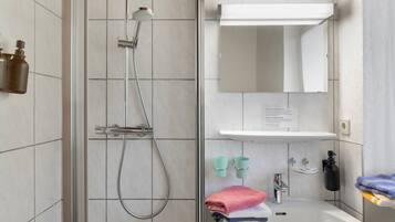 Ein Badezimmer mit Dusche, Waschbecken, Spiegel und Pflegeprodukten.