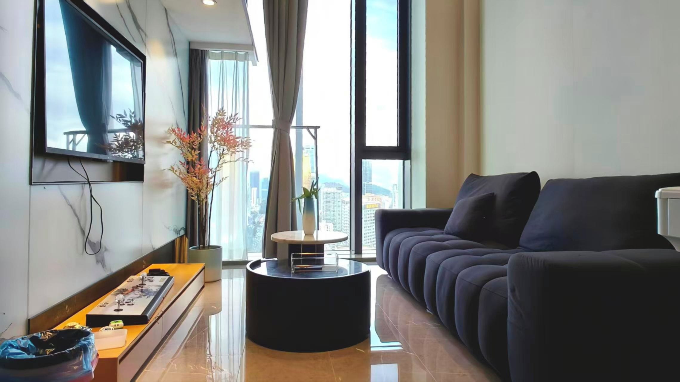 A modern living room with a sofa, a coffee table, and a flat-screen TV mounted on the wall.