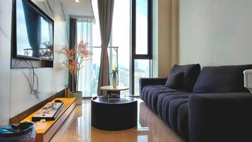 A modern living room with a sofa, a coffee table, and a flat-screen TV mounted on the wall.
