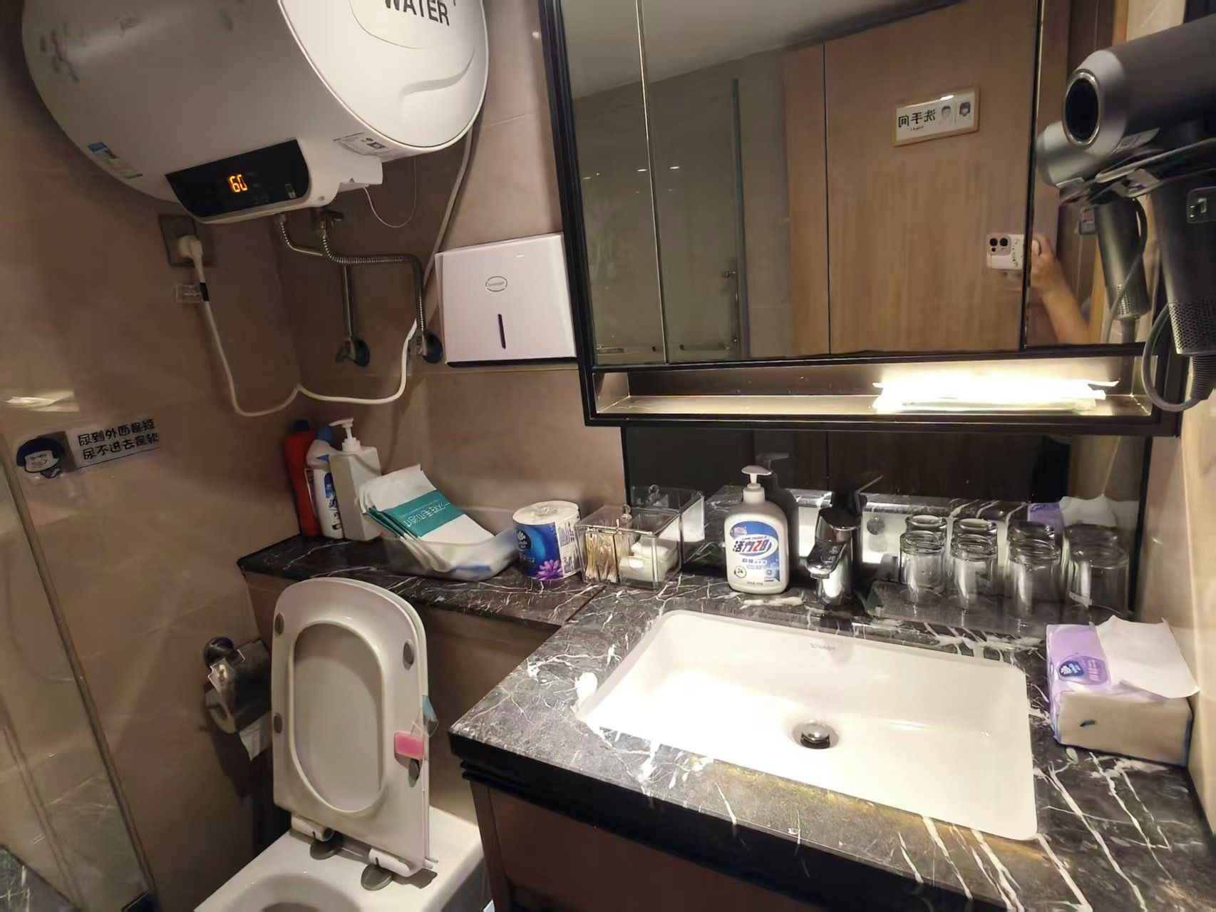 A bathroom with a sink, toilet, hand dryer, and a mirror.