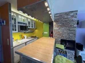 A modern kitchen with a wooden countertop, built-in microwave, and a stone fireplace. - Balcony, tv, 30m², Pra Loup (Pra Loup)