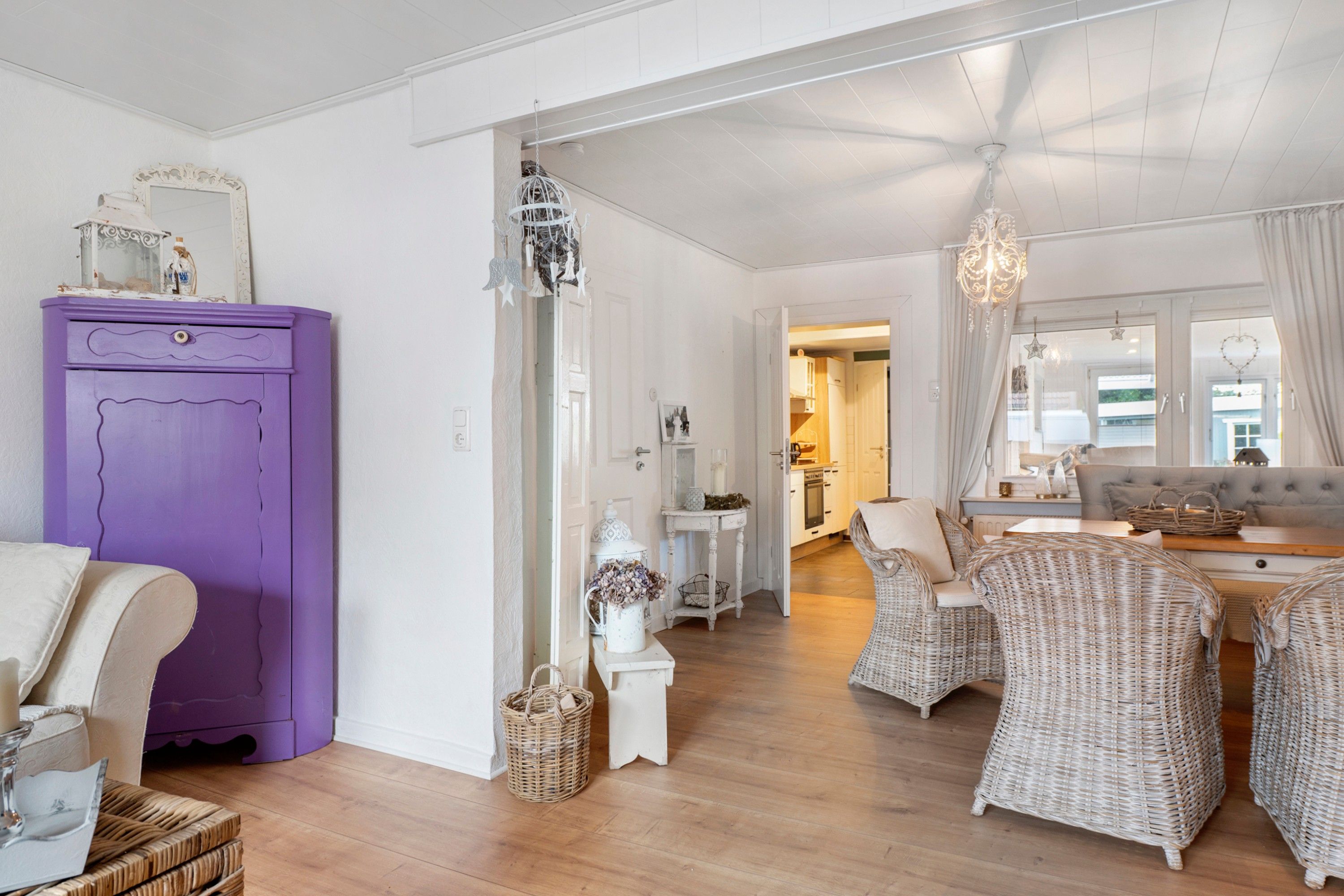 A room with a purple cabinet, wicker furniture, and a chandelier.