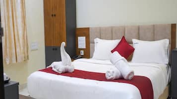 Quarto de hotel com uma cama, guarda-roupa de madeira, uma escrivaninha e um cobertor vermelho.