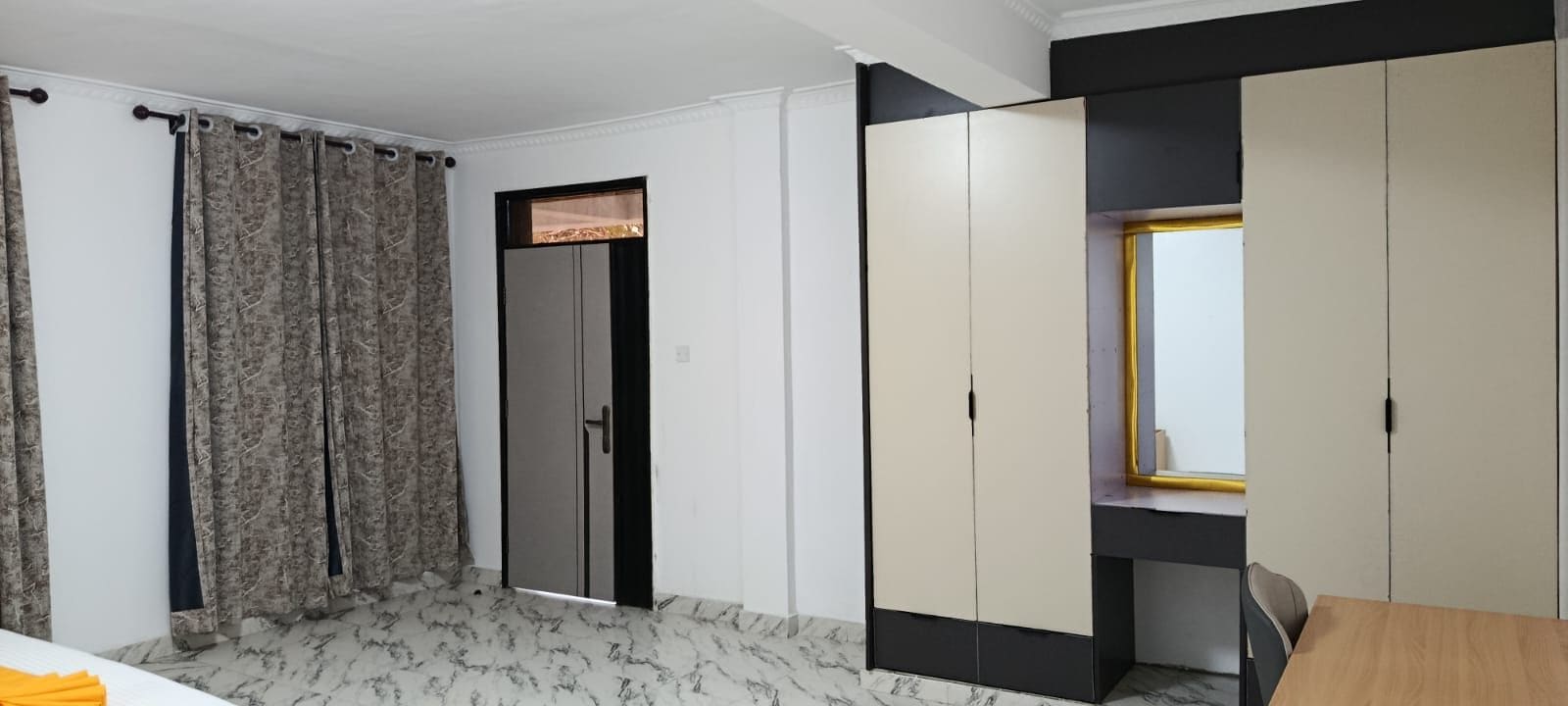 A room with a bed, a wardrobe, a desk, and a window.