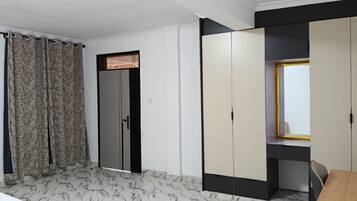 A room with a bed, a wardrobe, a desk, and a window.