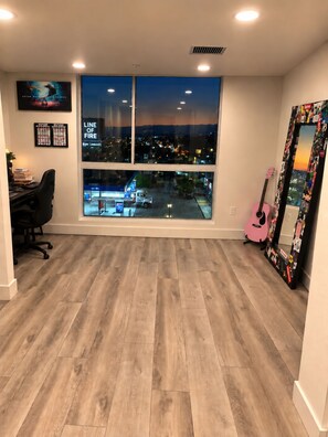 A room with a large window, a desk, a chair, a pink guitar, and a mirror with stickers. - Artist Safe House: Melrose Loft + 2 Baths (Los Angeles)