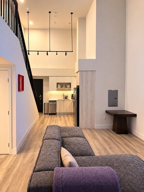 A modern interior with a staircase, a kitchen area, and a seating area with a sofa and ottoman. - Artist Safe House: Melrose Loft + 2 Baths (Los Angeles)
