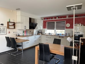 A modern kitchen with white cabinets, a wooden dining table, and black chairs. - Pet-friendly vacation home just 10 minutes away from Safari Park & Bird Park (Böhme)