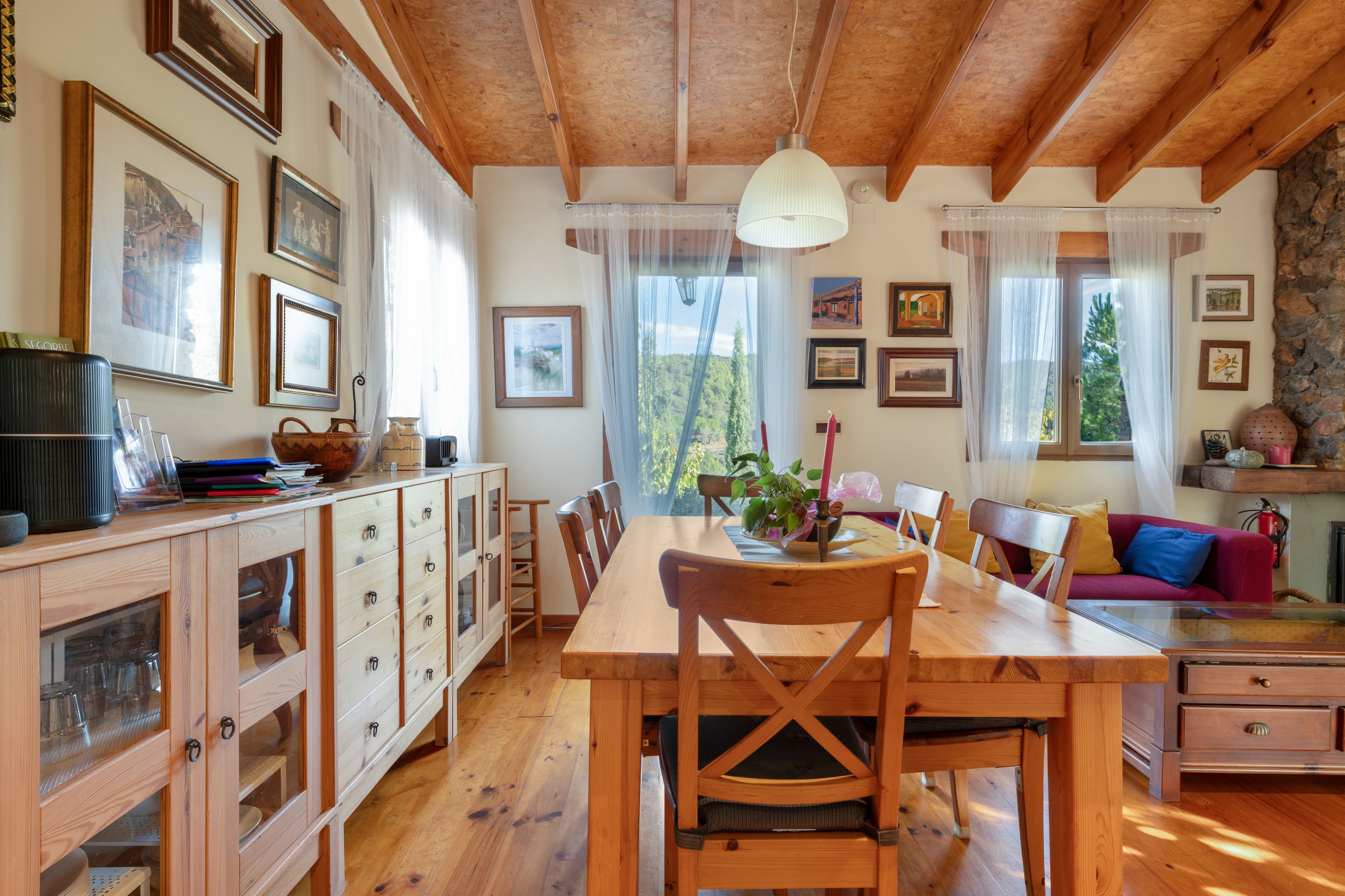 A wooden dining area with a table and chairs, a kitchen with cabinets, and a living area with a sofa and a fireplace.