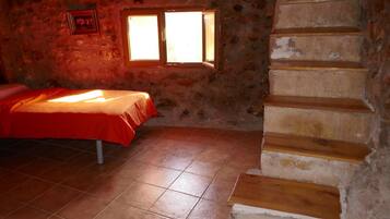 A room with a bed, a window, and a wooden staircase.