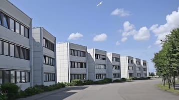 Ein modernes Gebäude mit mehreren Stockwerken, großen Fenstern und einem Parkplatz.