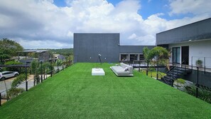 A modern outdoor space with artificial grass, a white sofa, and a telescope. - Celias Beautiful House (Tibau do Sul)