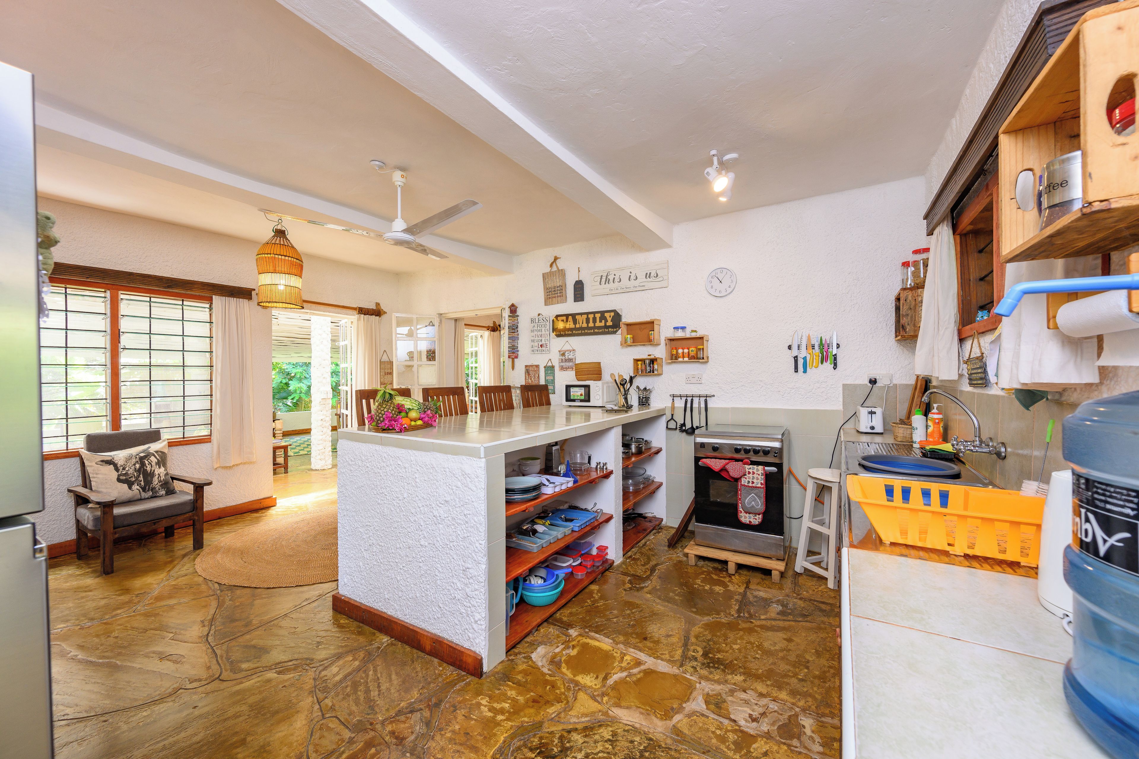 Una cocina amplia con una isla central, armarios de madera y piso de piedra.