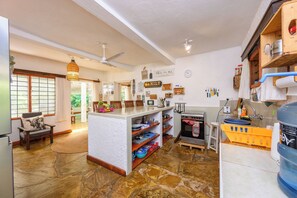 Una cocina amplia con una isla central, armarios de madera y piso de piedra.