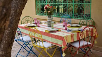 Una mesa para cuatro con mantel a rayas, sillas de metal y un jarrón con flores.