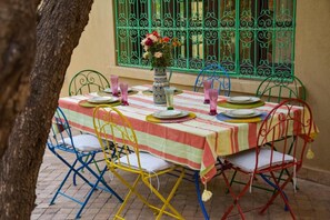 A table set for four with a striped tablecloth, metal chairs, and a vase with flowers.