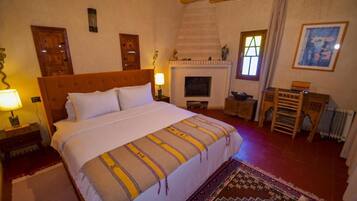 A bedroom with a large bed, a fireplace, a wooden headboard, and a rug.