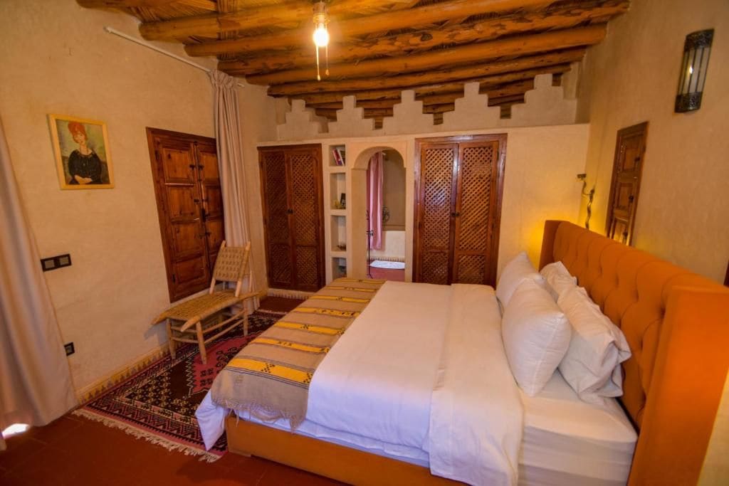 Una habitación con una cama, una silla y techo de madera.