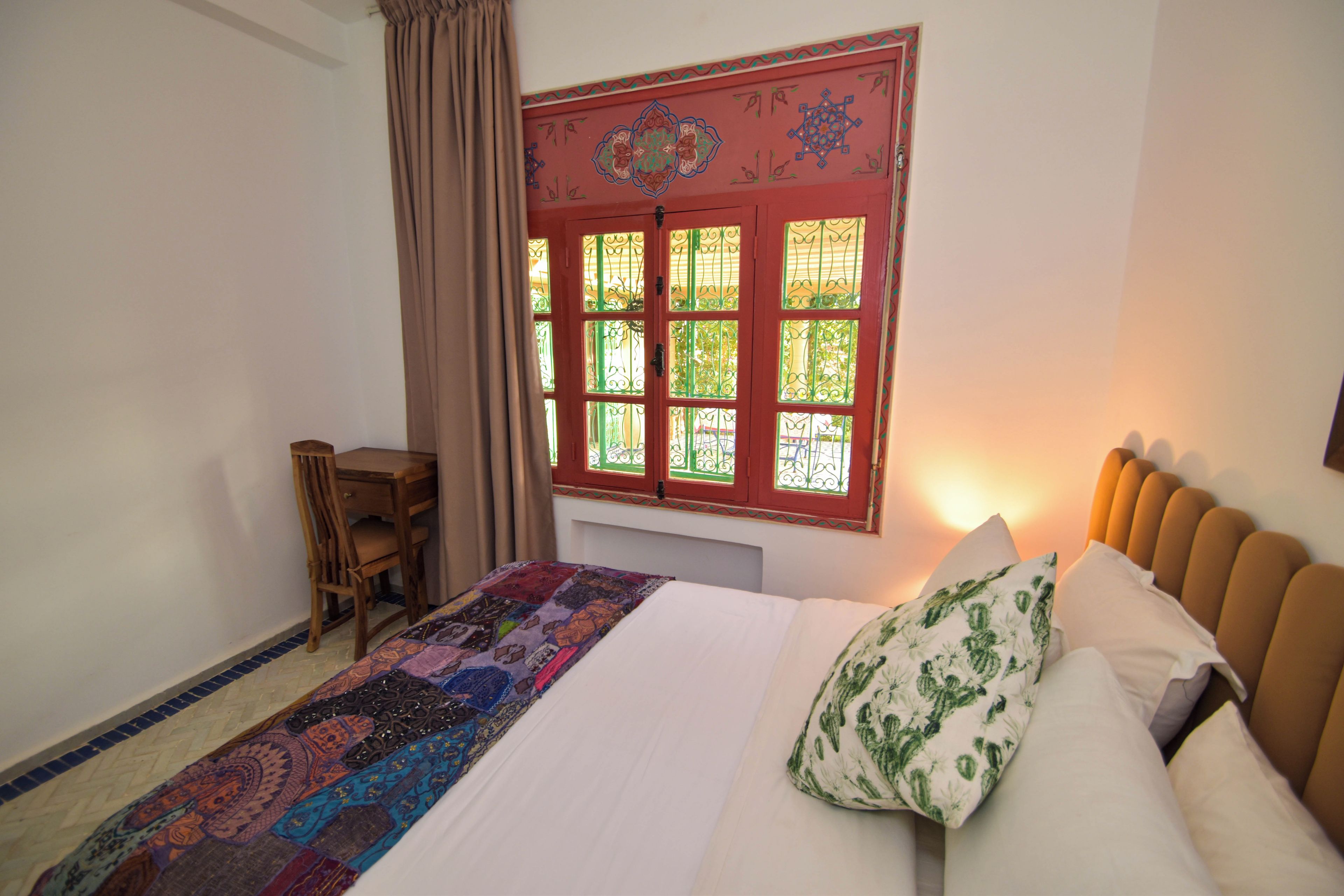 Une chambre à coucher comprenant un lit, un bureau et une fenêtre agrémentée d’éléments décoratifs.