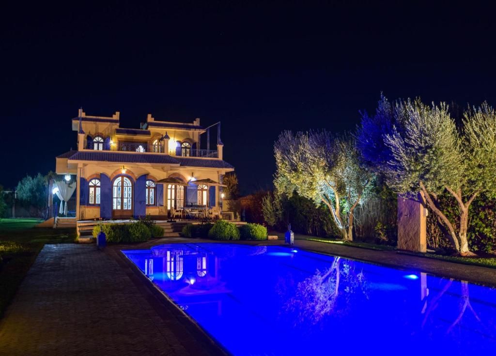 Un edificio grande e iluminado con una piscina delantera.