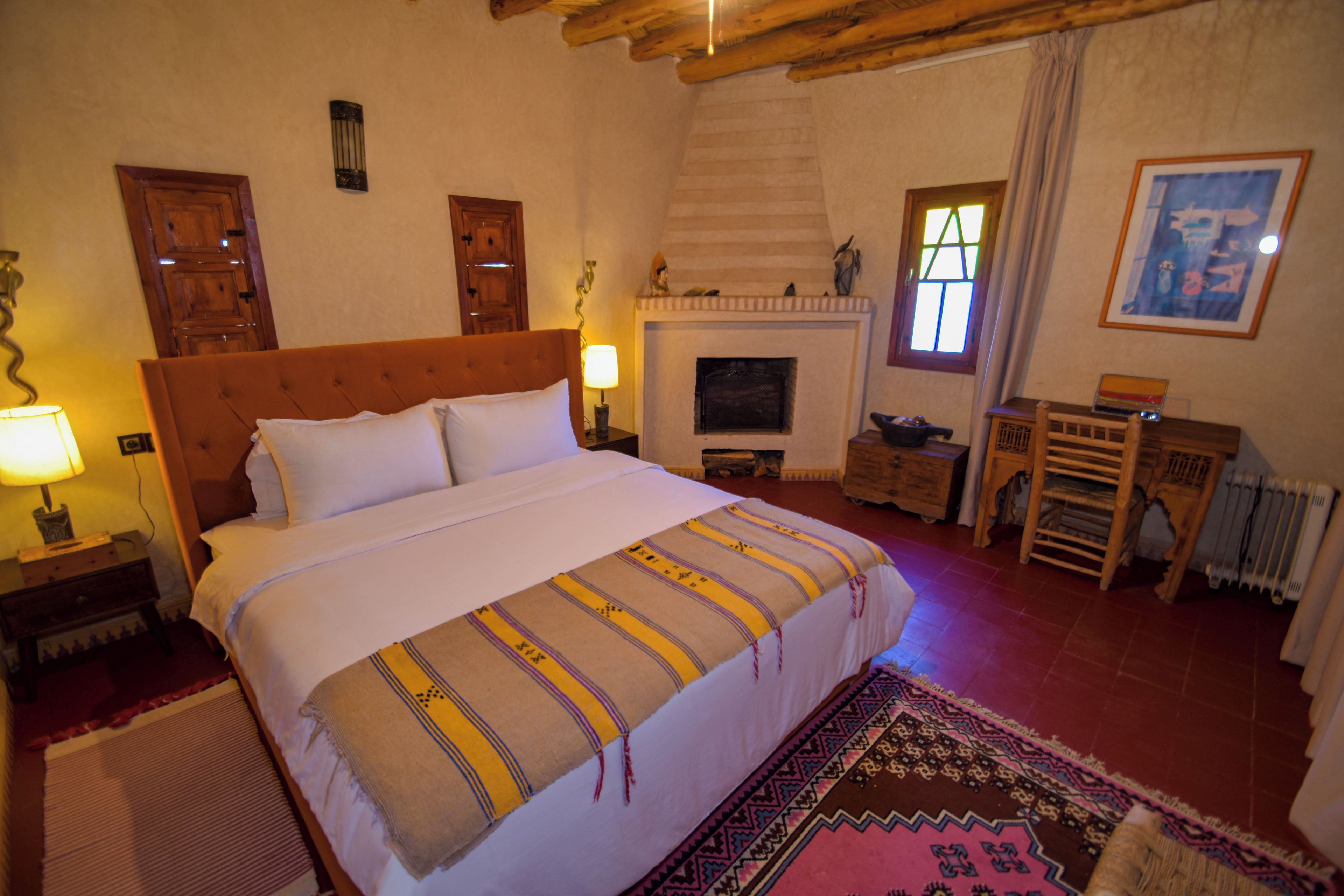Un dormitorio con una cama grande, chimenea, muebles de madera y vistas al exterior.