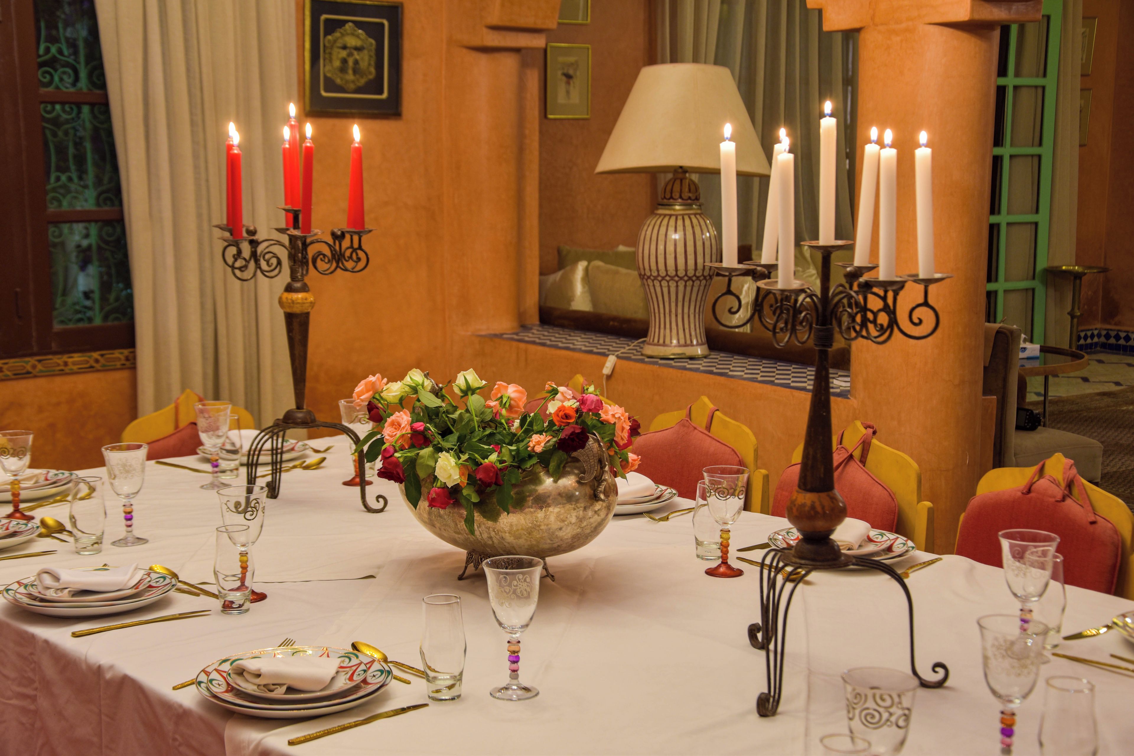 Mesa de comedor dispuesta con platos, cubiertos, vasos y una pieza central con flores.