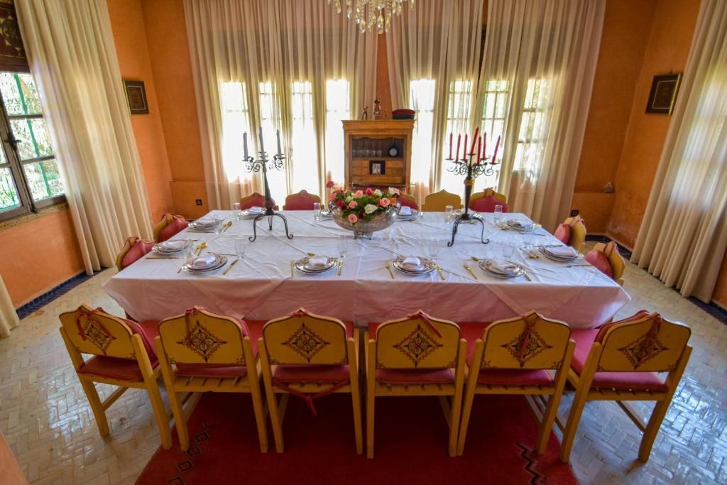 A dining room with a round table set for six, surrounded by six chairs with a red and yellow color scheme.