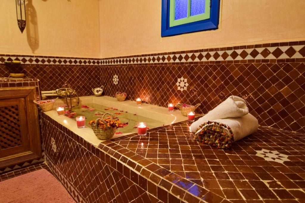 A bathroom with a tiled floor, a bathtub, candles, and towels.