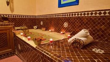 A bathroom with a tiled floor, a bathtub, candles, and towels.