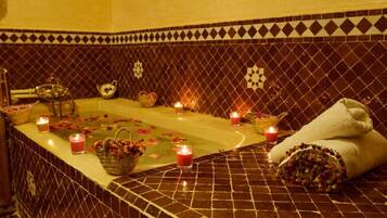 Un área de spa con bañera, velas y toallas.