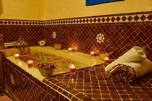 A spa area with a bathtub, candles, and towels.