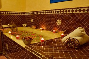 A spa area with a bathtub, candles, and towels.