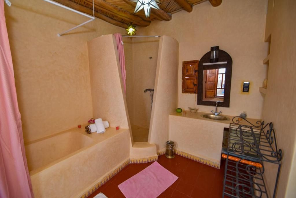 Un baño con ducha, lavamanos, espejo y barra para toallas.