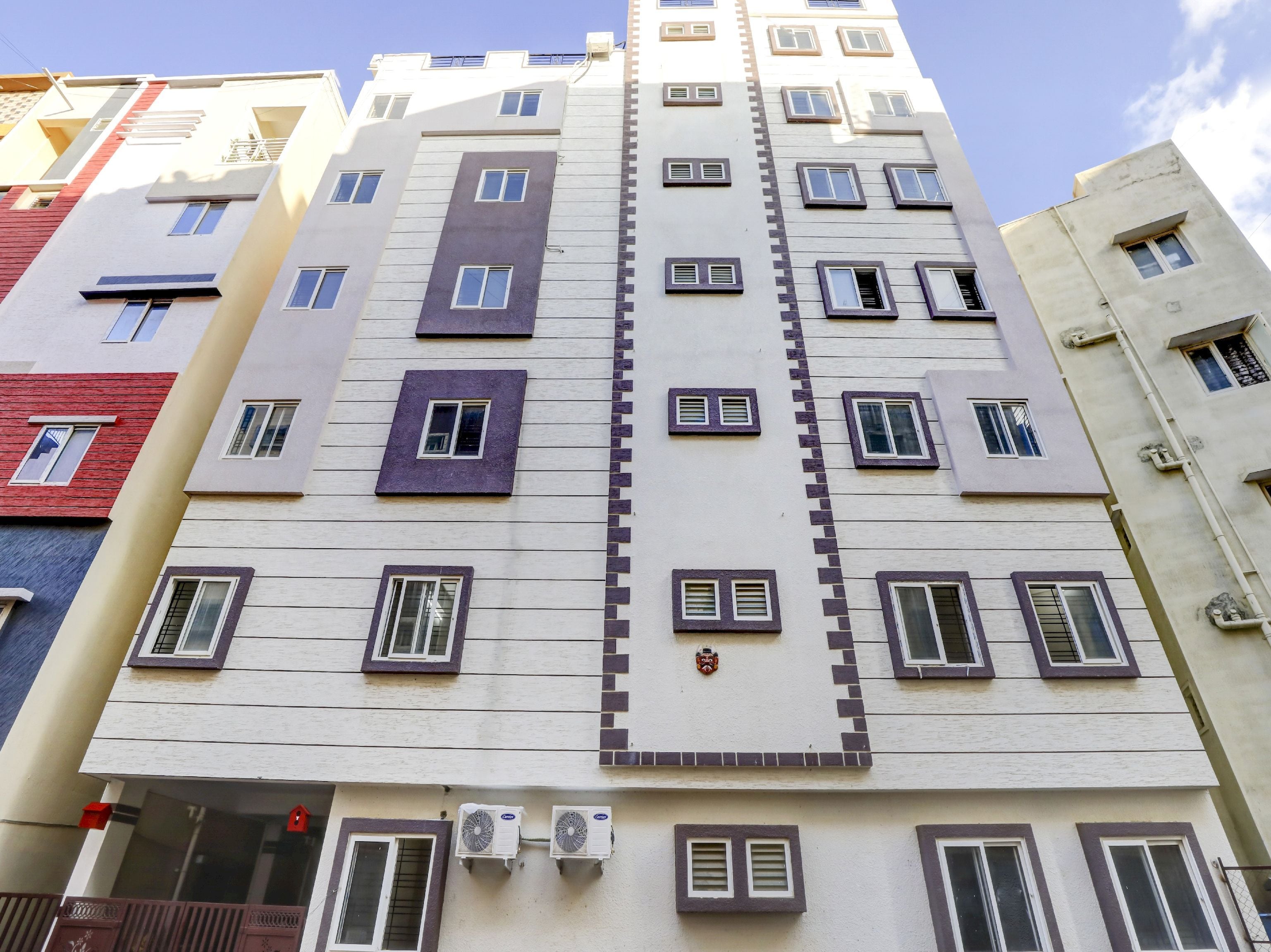 Un edificio de varios pisos con un diseño arquitectónico moderno, que presenta un elemento vertical central y numerosas ventanas.