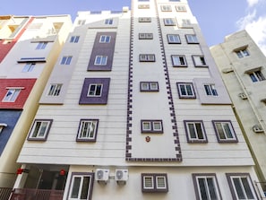 A multi-story building with a modern architectural design, featuring a central vertical element and multiple windows. - Hotel O The Purple Orchid (Bengaluru)