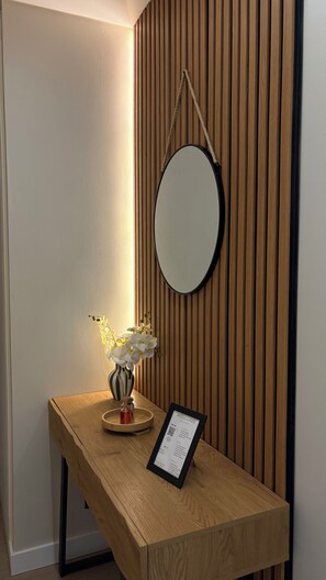 A reception desk with a mirror, a framed welcome sign, and a vase with white flowers. - Rio in Sight. Apartment in downtown Portimão with a view of the waterfront. (Portimão)