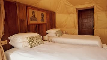 Une chambre avec deux lits, une tête de lit en bois, un tableau encadré et une porte.