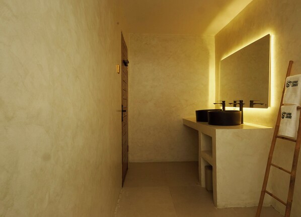 A bathroom with a large mirror, a wooden ladder, and a sink with a black basin.