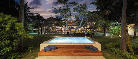 A pool area with wooden loungers and a view of a building in the background.