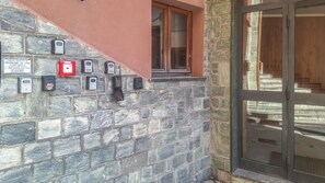 A stone wall with multiple intercoms and a red emergency button. - GRAN PARADIS - Panoramic Apartment in Aprica / San Pietro (San Pietro)