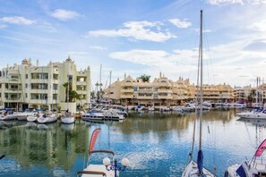 A marina with multiple boats docked, a large building with multiple balconies, and a clear sky. - BENALBEACH SEA VIEW apartment with water park (Benalmádena Costa)