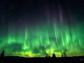 A night sky with visible stars and green aurora borealis.