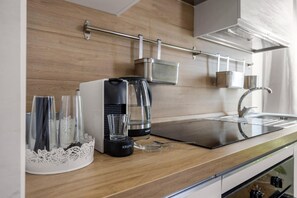 Eine moderne Küche mit Kaffeemaschine, Wasserkocher und einem Glaskrug auf der Arbeitsfläche.