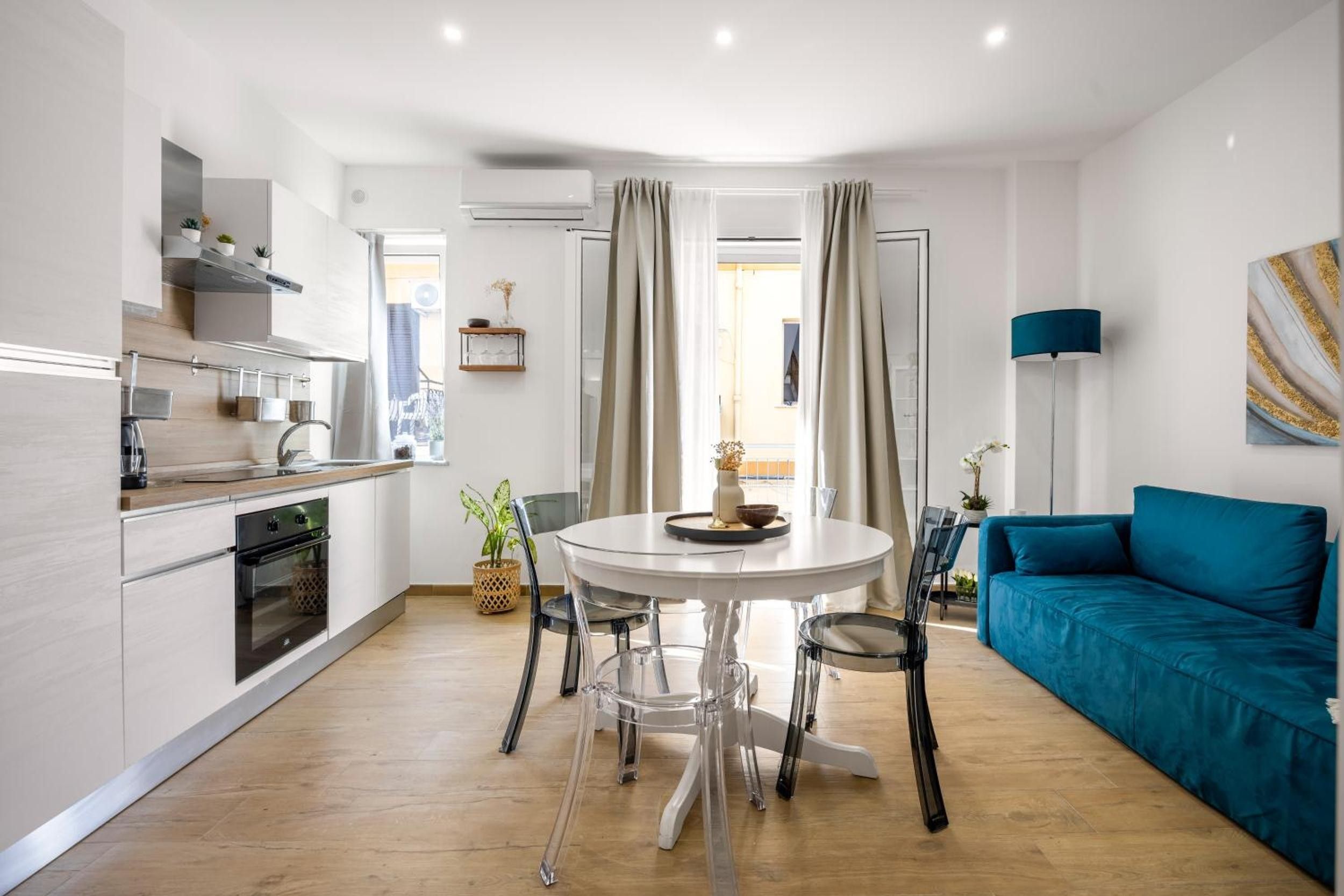 Une cuisine moderne avec un coin repas, un canapé bleu et une vue sur l’extérieur.