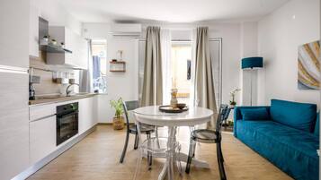 Une cuisine moderne avec un coin repas, un canapé bleu et une vue sur l’extérieur.