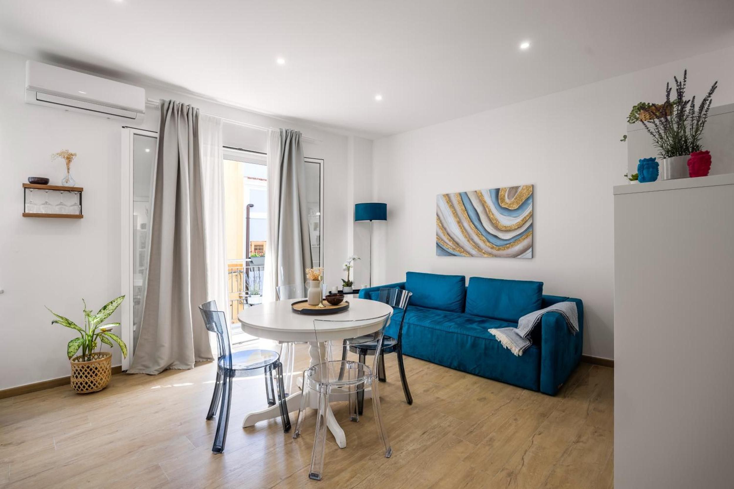 Un salon moderne avec un canapé bleu, une table à manger avec des chaises et un tableau accroché au mur.